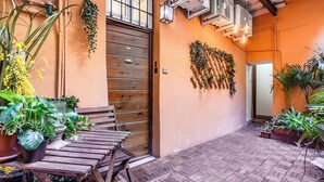 Una puerta de madera, equipos de aire acondicionado y plantas en macetas.
