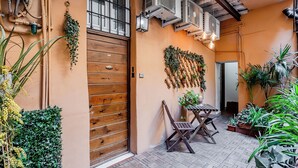 Un patio con puerta de madera, unidades de aire acondicionado y plantas en macetas.