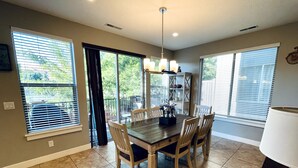 A dining area with a wooden table and chairs, a chandelier, and a view of the outdoors through large windows. - Entrada at Moab 598 and 602 | Townies | Pool/Spa | Garage | Same Day Booking (Moab)