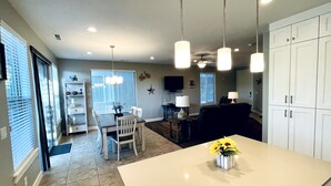 A spacious kitchen with a central island, dining area with chairs, and a living room with a couch. - Entrada at Moab 598 and 602 | Townies | Pool/Spa | Garage | Same Day Booking (Moab)