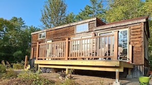 Une cabane en bois dotée d’une terrasse, entourée d’arbres.