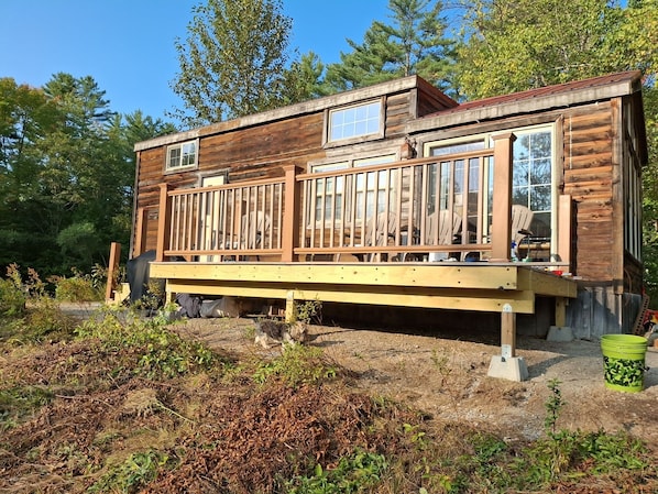 A wooden cabin with a deck, surrounded by trees.