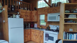 Une cuisine de style rustique, avec des meubles en bois, un réfrigérateur, une cuisinière, un four à micro-ondes et une bibliothèque.