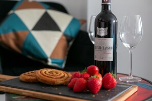A bottle of Chianti Classico Riserva wine, a glass, and pastries with strawberries on a tray.