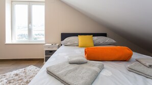 Une chambre à coucher avec un lit, des oreillers, une table de chevet et une fenêtre.