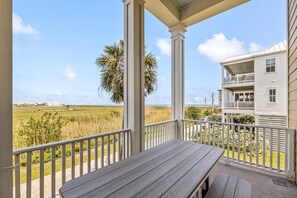 A wooden deck with a view of a beach and a white building with a balcony. - Beachtown: Beautiful Townhome w/ Beach Views & Elevator! Short Walk to Beach! (Galveston)