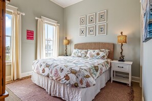 A bedroom with a bed, bedside tables, a lamp, and framed pictures on the wall. - Beachtown: Beautiful Townhome w/ Beach Views & Elevator! Short Walk to Beach! (Galveston)
