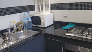 A kitchen with a sink, stove, microwave, and cabinets. - Apparemment Agréable Idéal Pour Famille (Agadir)