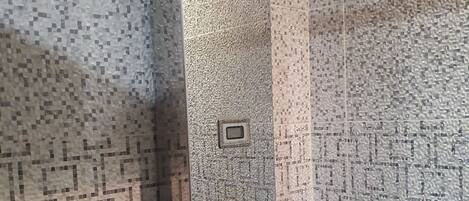 A bathroom with mosaic tile walls and a glass shower enclosure.