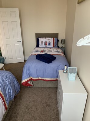 Une chambre à coucher avec un lit, une table de chevet, une lampe et une petite table sur laquelle se trouve une autre lampe.