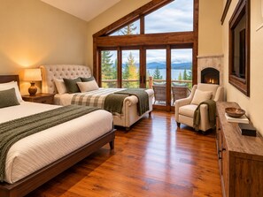 Un dormitorio con una cama grande, una cama más pequeña, una chimenea y vistas al exterior.