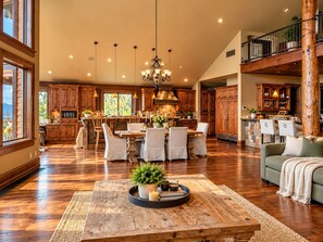 Una cocina amplia con armarios de madera, un comedor con una mesa grande y sillas, y una sala de estar acogedora con un sofá.