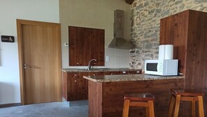 Eine Küche mit Holzschränken, einer Granit Arbeitsplatte, einer Mikrowelle und zwei Barhocker.