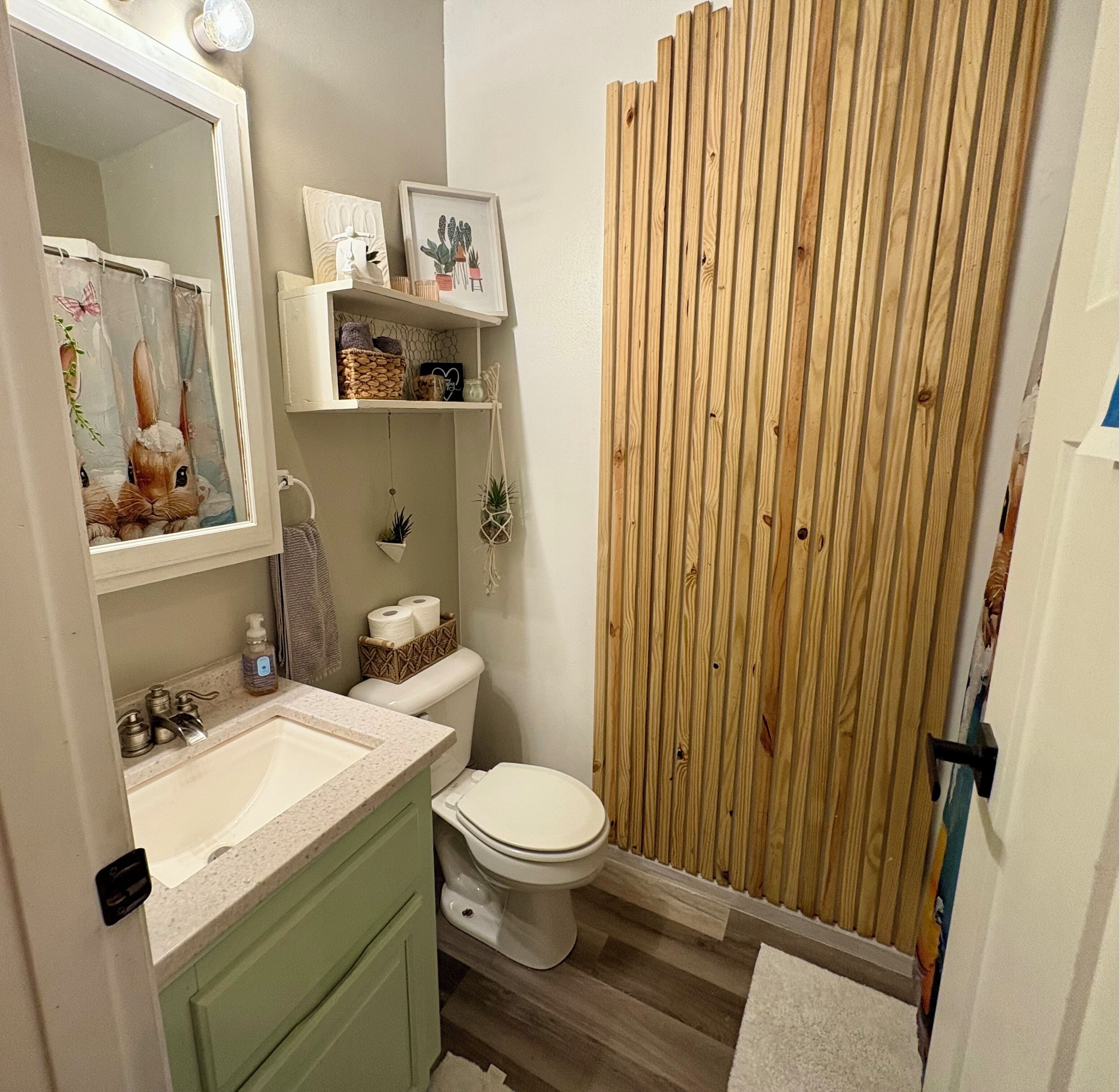 Un baño con cabina de ducha de madera, un lavamanos con espejo y un inodoro.