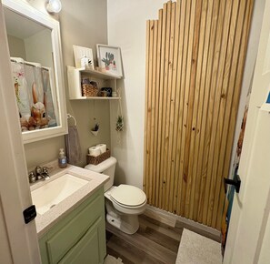 A bathroom with a wooden shower enclosure, a sink with a mirror, and a toilet.