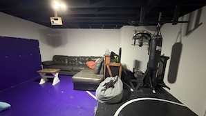 Habitació amb un sòl morat, un sac de boxa negre, un sofà de pell i una taula de fusta petita.