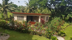 Une maison avec un toit rouge, entourée d’une végétation luxuriante et d’un jardin bien entretenu.
