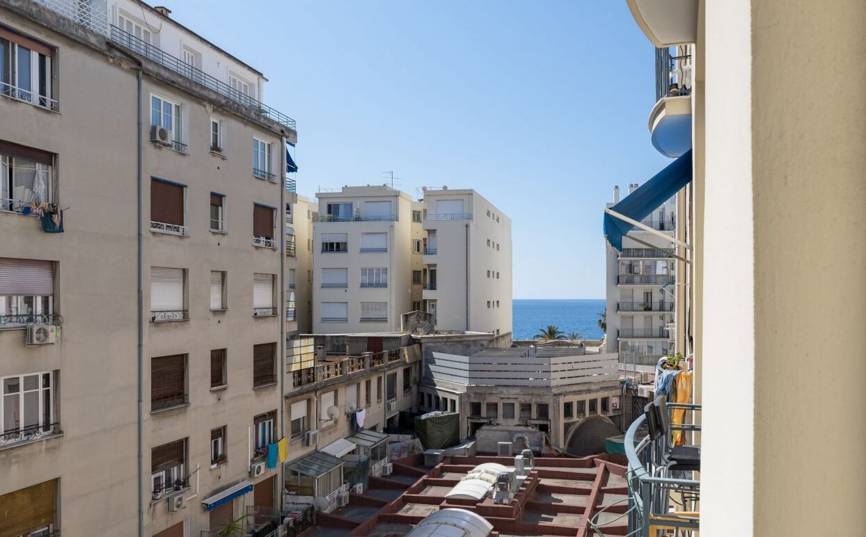 A view of a coastal urban area with multi-story buildings, balconies, and a clear view of the sea.