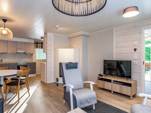 A modern living room with a television, a dining area with chairs, and a kitchen with wooden cabinets. - Järvenhelmi by Interhome (Valkeala)