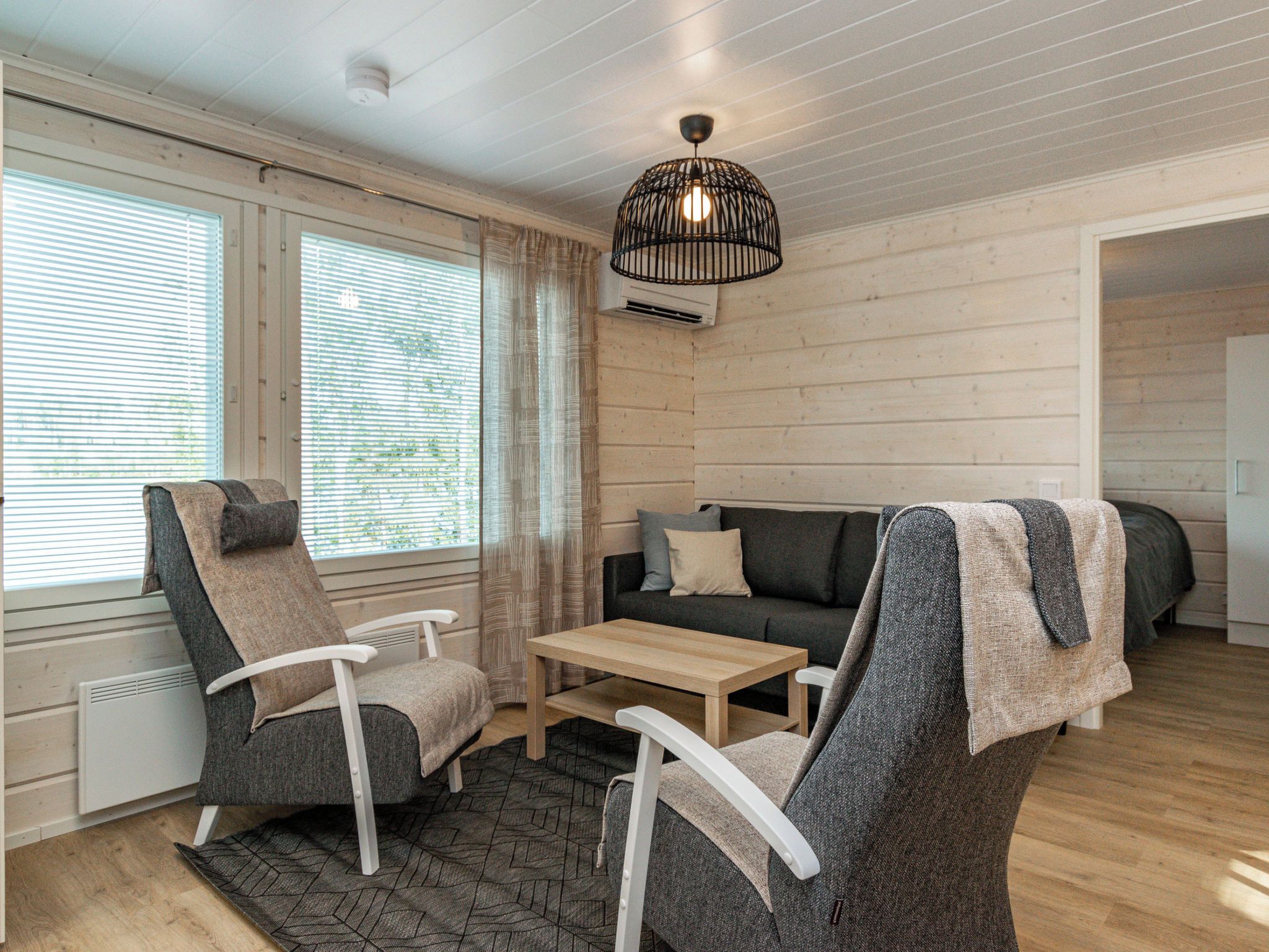 Una habitación acogedora con un sofá, dos sillones, una mesa de centro y una lámpara colgante.