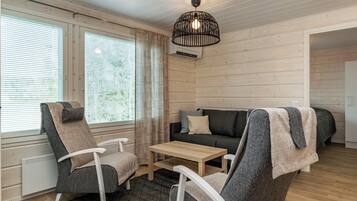 Una habitación acogedora con un sofá, dos sillones, una mesa de centro y una lámpara colgante.