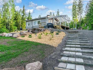 Una cabaña moderna con un espacio exterior cubierto, rodeada de un bosque.