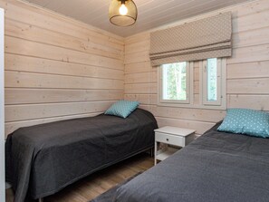Una habitación con dos camas, una mesita de noche pequeña y un ventanal con un cortinero estampado de lunares.