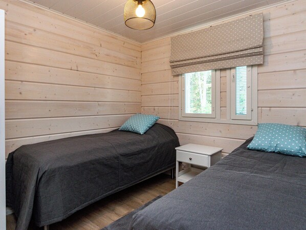 Una habitación con dos camas, una mesita de noche pequeña y un ventanal con un cortinero estampado de lunares.