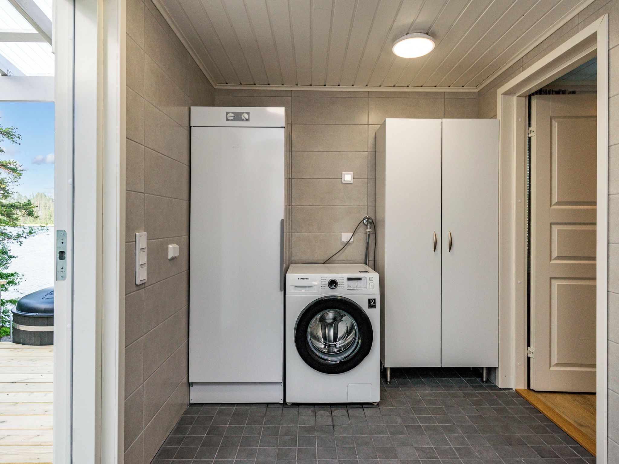 Een kleine wasruimte met een wasmachine, een droger en een kast.