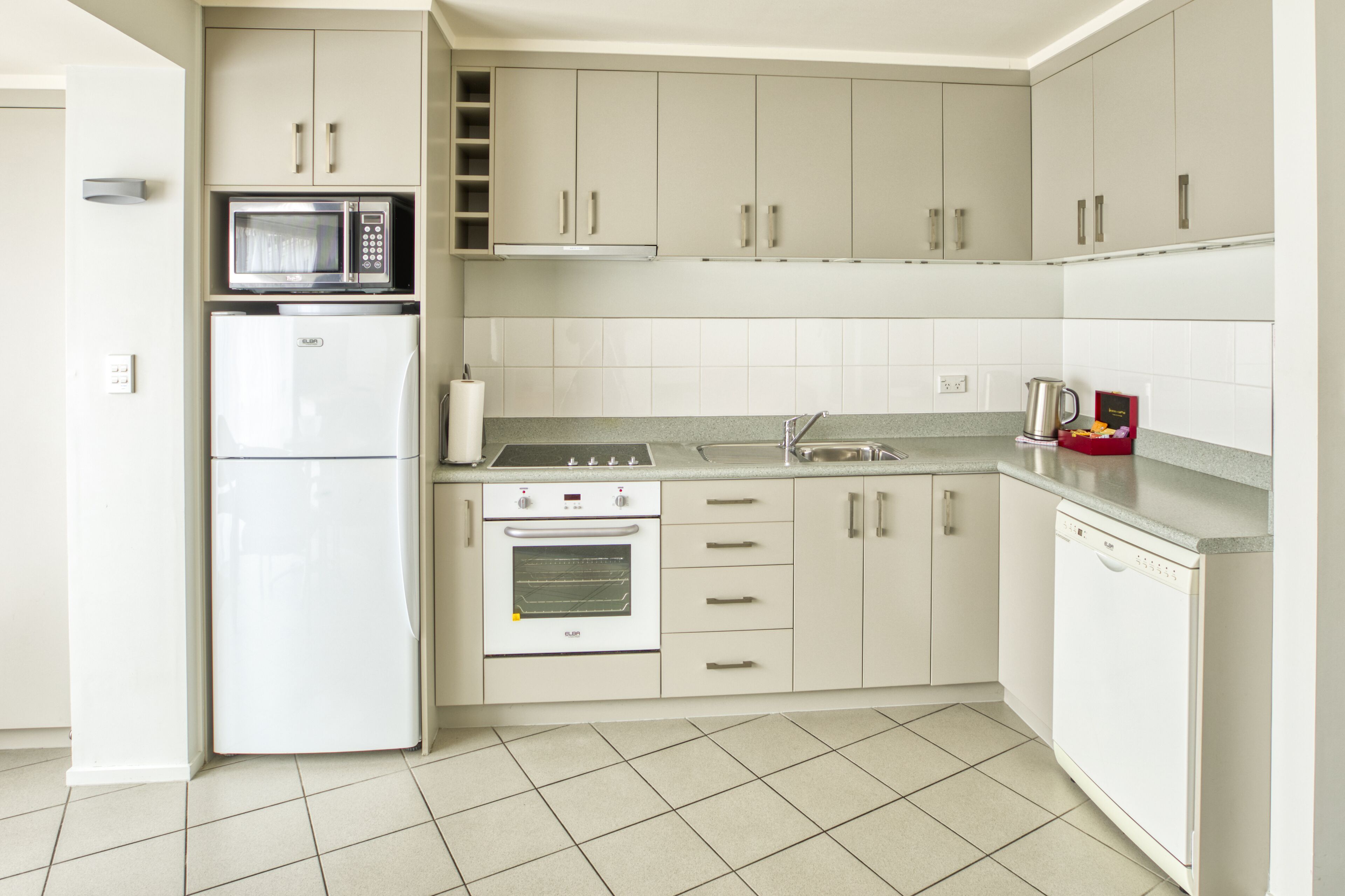 A modern kitchen with white cabinets, a microwave, a refrigerator, an oven, and a dishwasher.