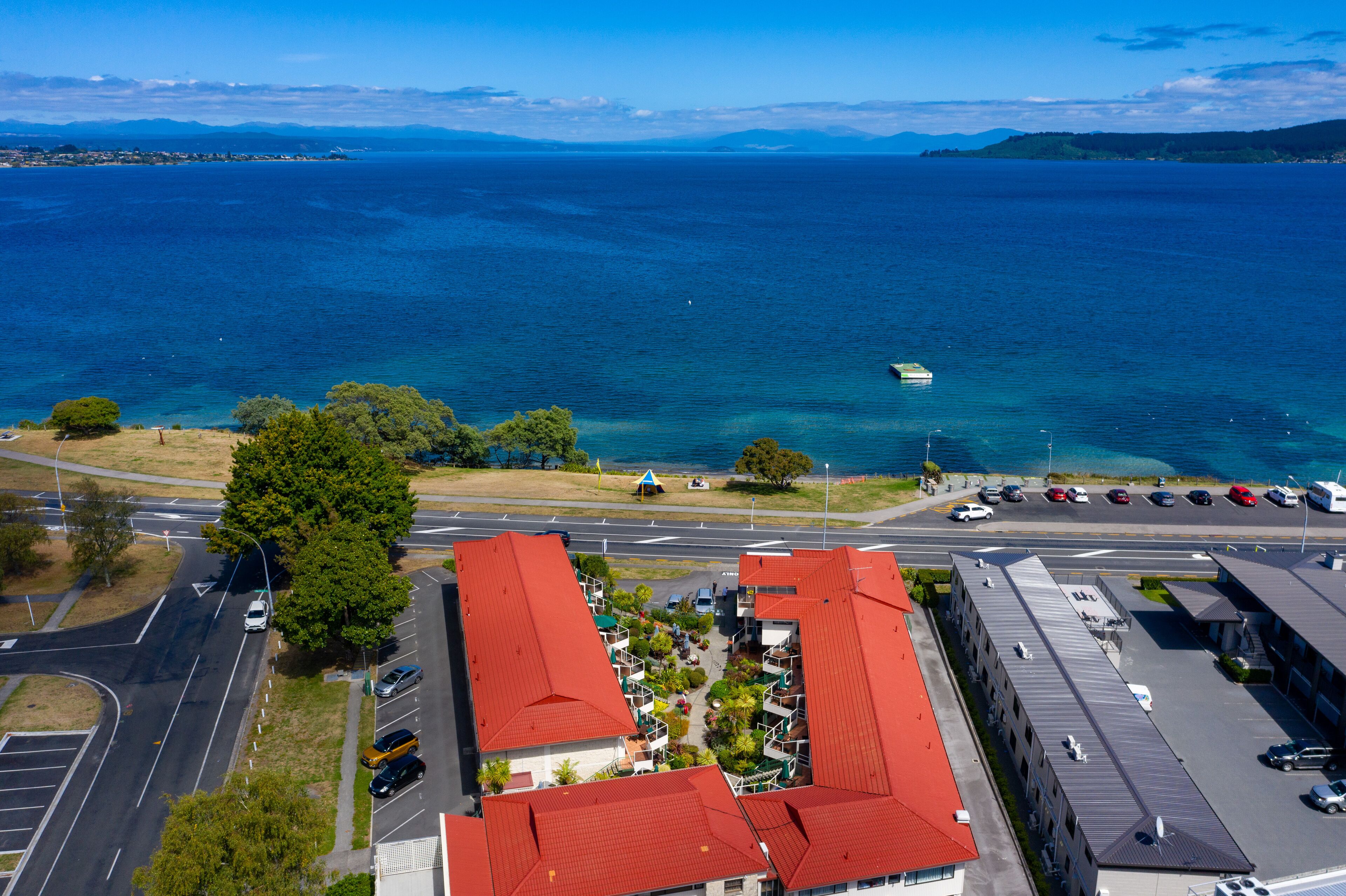 Un hôtel situé sur la côte, avec des toits rouges, un parking et une vue sur la mer.