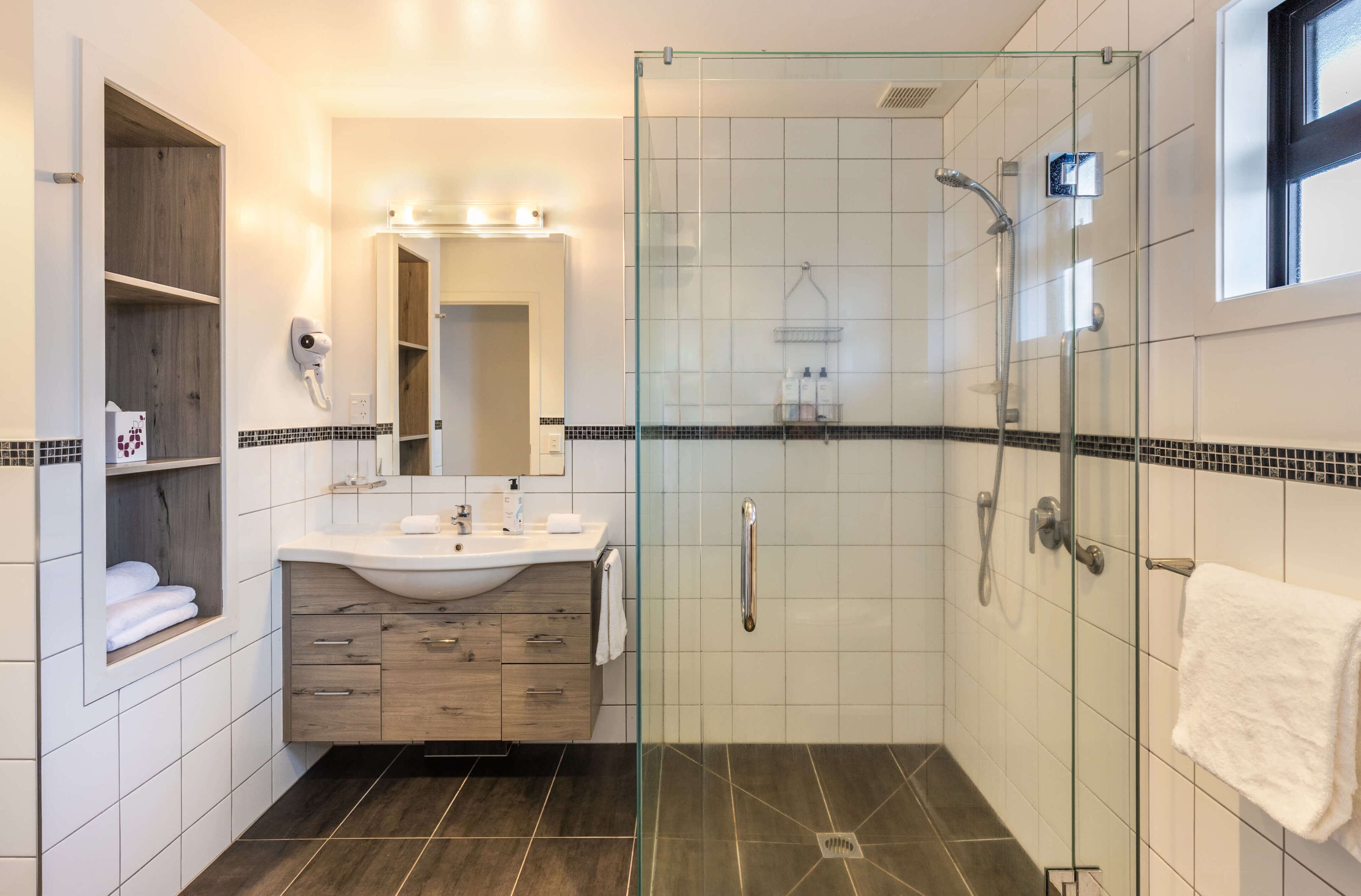 A modern bathroom with a glass-enclosed shower, a vanity with a mirror, and a towel rack.