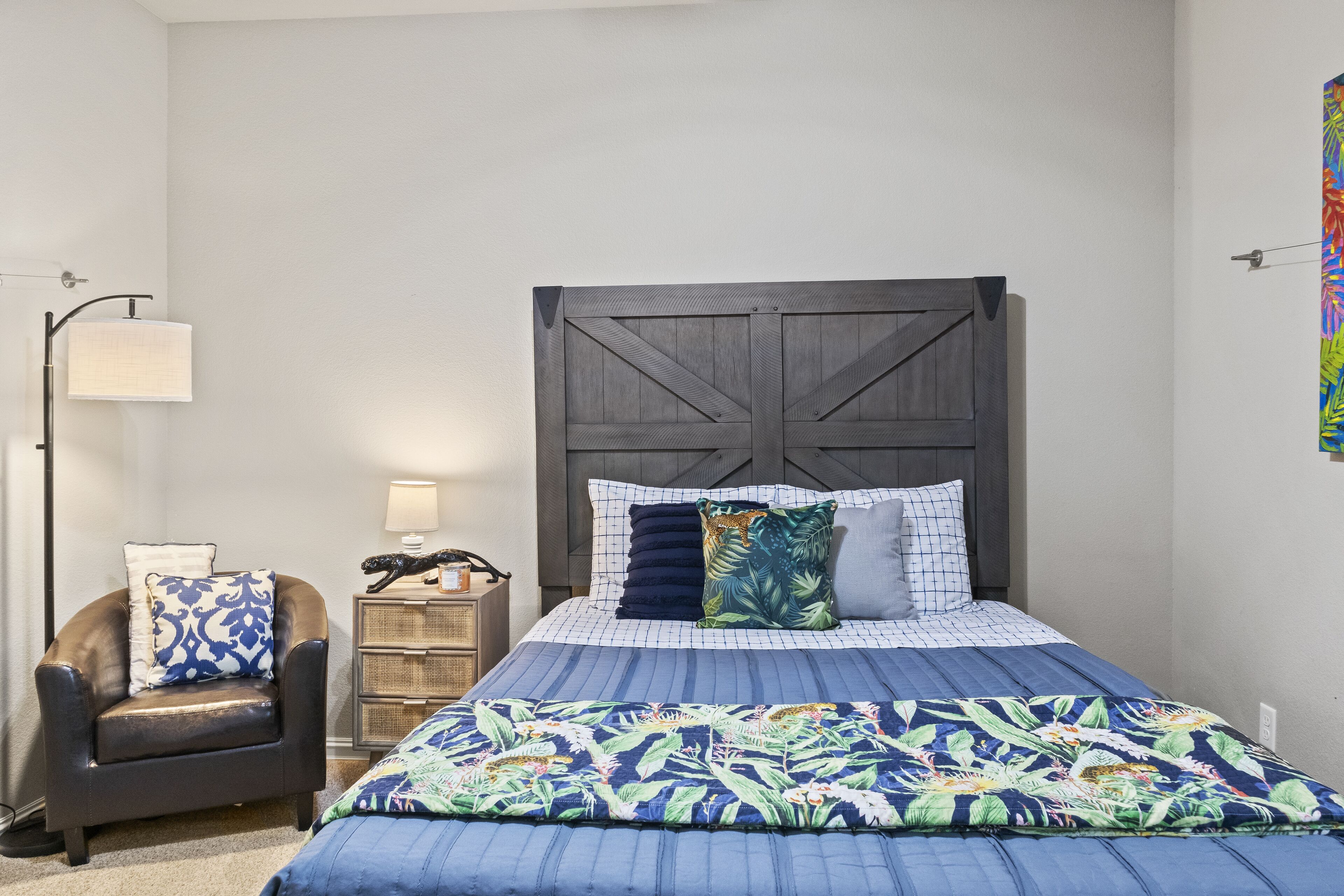 Une chambre à coucher avec un lit, une chaise, une table de chevet et une lampe.