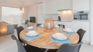 Un área de comedor moderna con una mesa redonda de madera, sillas negras y manteles individuales azules.