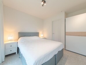 Quarto moderno com uma cama de solteiro, mesas de cabeceira, guarda-roupa e uma luminária no teto.