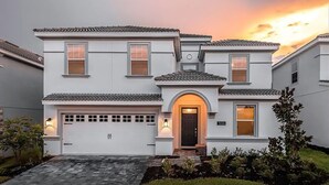 Une maison à deux étages, à l’extérieur blanc, avec un garage et une cour avant bien entretenue.