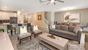 Un salon moderne avec un canapé gris, une table basse et un coin repas avec des chaises.