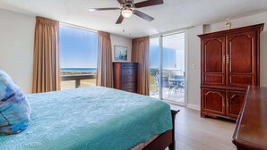 Una camera da letto con un letto, una ventola a soffitto, un armadio in legno e vista sulla spiaggia.