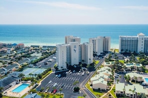 A high-rise hotel with multiple floors, a parking lot, and a pool area. - Beachfront Condo in the heart of Destin! (Destin)