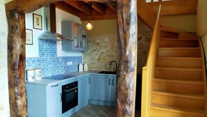 Una cocina con armarios azul claro, una pared de piedra y una escalera de madera.