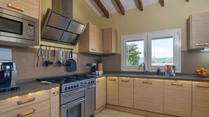 A modern kitchen with stainless steel appliances, wooden cabinets, and a window providing a view of the outdoors. - El Elefante 4 pax - Javea, Costa Blanca (Javea)
