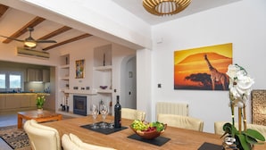 A spacious living area with a wooden dining table, comfortable seating, a fireplace, and a large painting of a giraffe. - El Elefante 4 pax - Javea, Costa Blanca (Javea)