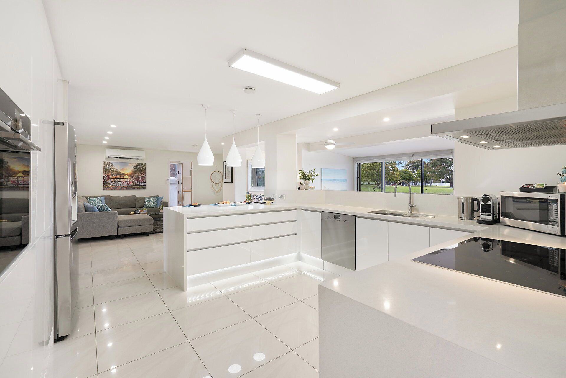 A modern kitchen with a central island, built-in appliances, and pendant lighting.