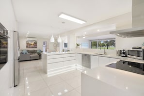 Een moderne keuken met een centraal eiland, inbouwapparatuur en hanglampen.