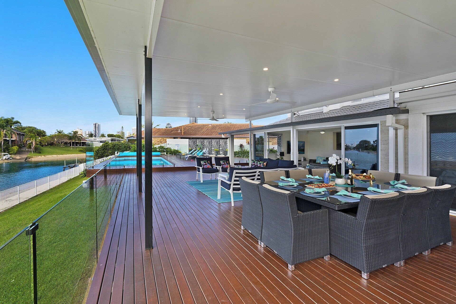 A covered outdoor area with a pool, seating, and a view of the water.