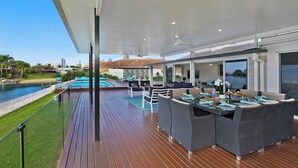 Un espace extérieur abrité avec une piscine, des sièges et une vue sur l’eau.