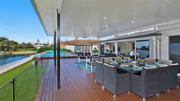 A covered outdoor area with a pool, seating, and a view of the water.