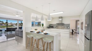 Une cuisine moderne dotée d’un îlot central, de tabourets de bar, d’un coin repas avec vue et d’un grand réfrigérateur.