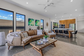 A modern living room with a leather sofa, a glass coffee table, and a dining area with a wooden table and chairs.