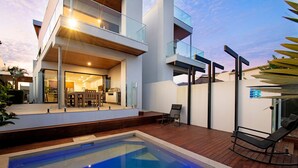 Une maison moderne dotée d’une piscine, d’un coin repas et d’un balcon.